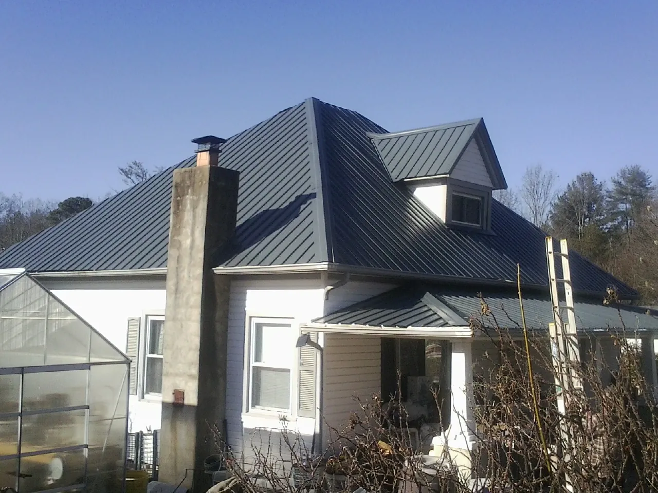 Dark blue standing seam metal roof on a white farmhouse with dormer — Slate & Tile Roof Repair by Roofing Brothers in Coal City