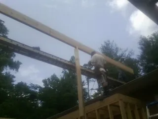 Carpenter setting a ridge beam over a new addition frame — Ice Dam Removal by Roofing Brothers in Coal City