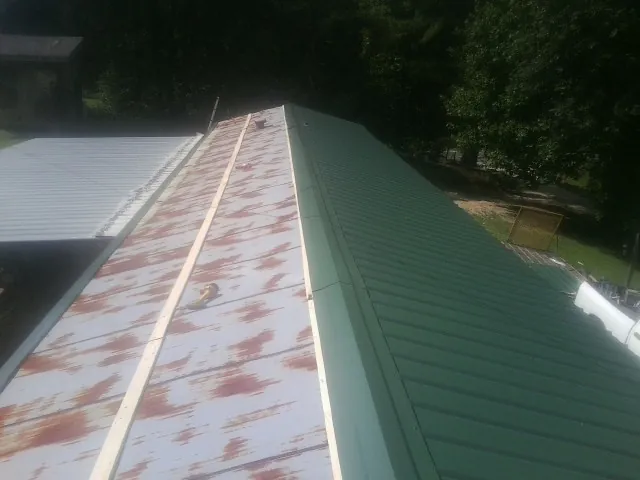 Old rusted panels beside newly installed green metal roofing — Wind Damage Roof Repair by Roofing Brothers in Coal City