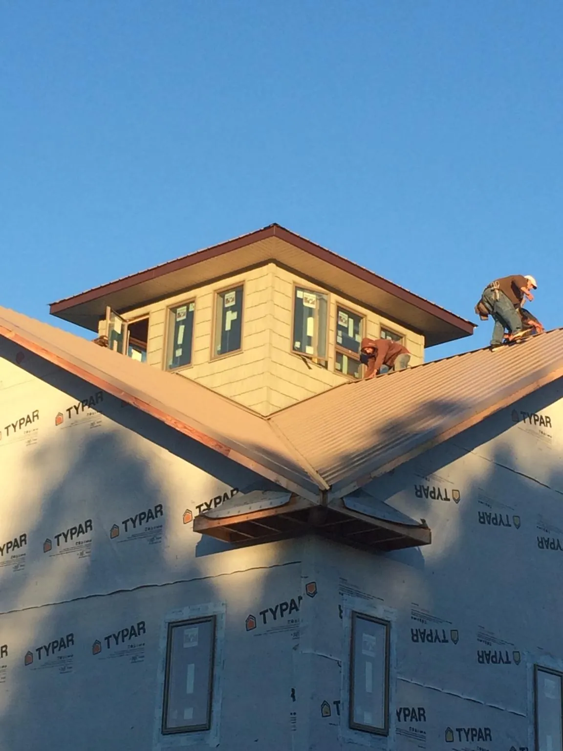 Roofers working around a rooftop cupola on a new metal roof at sunset — Roof Waterproofing in Coal City by Roofing Brothers